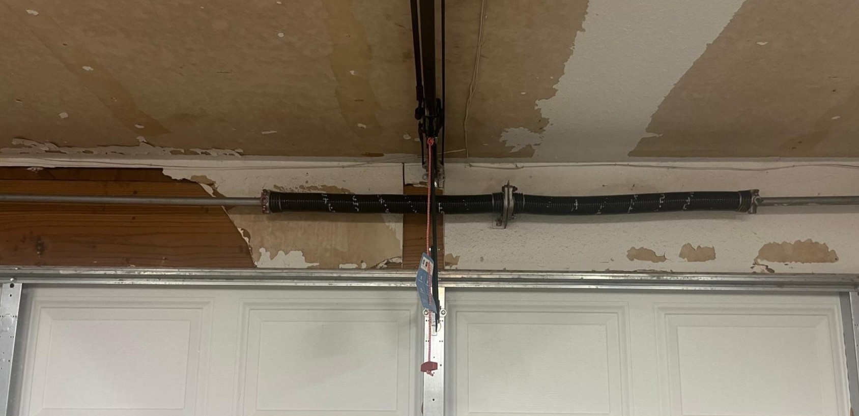 Garage door spring repair Dallas showing a torsion spring system above a residential garage door.