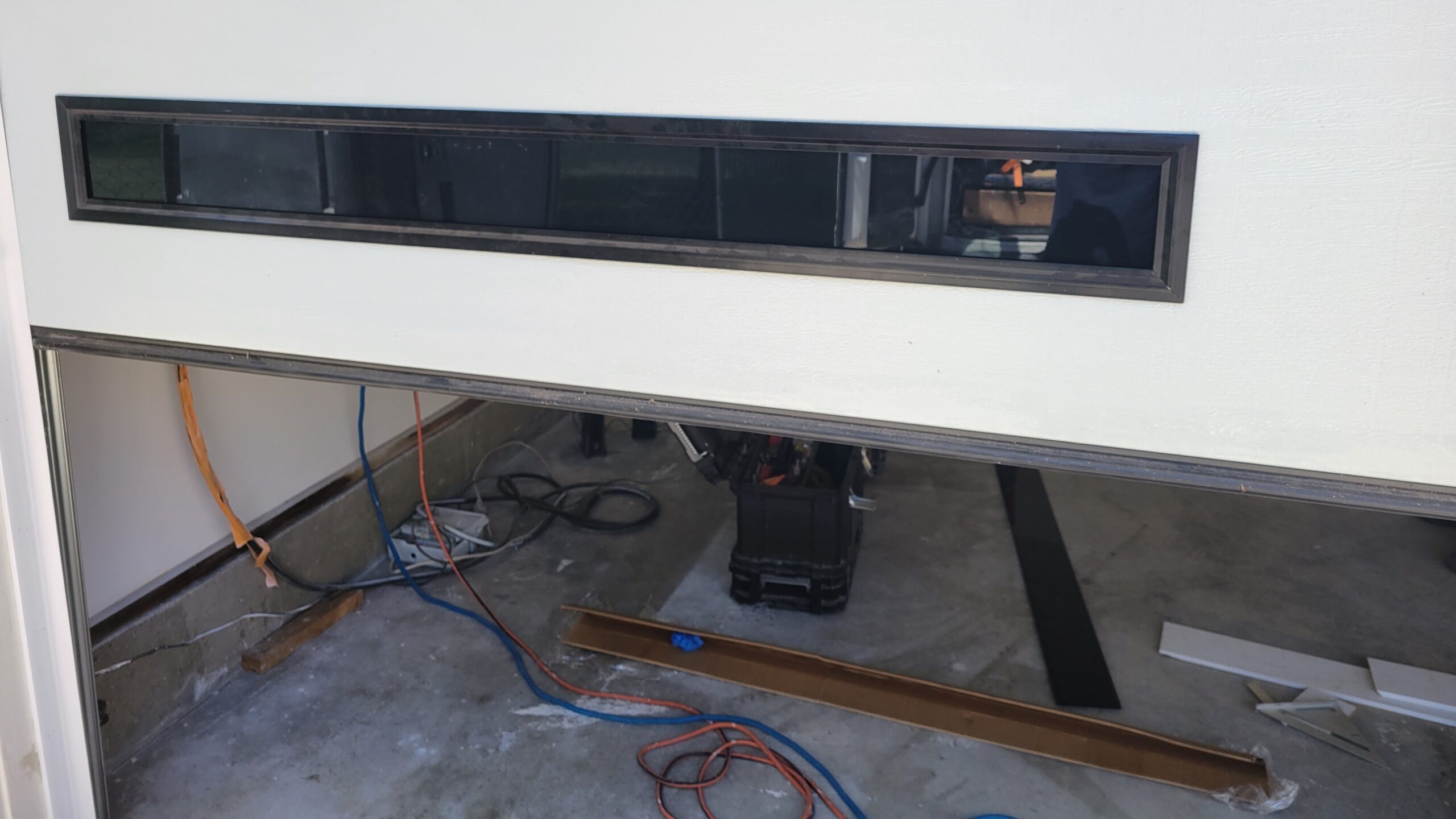 Garage door service for an open white residential garage door with black horizontal windows.