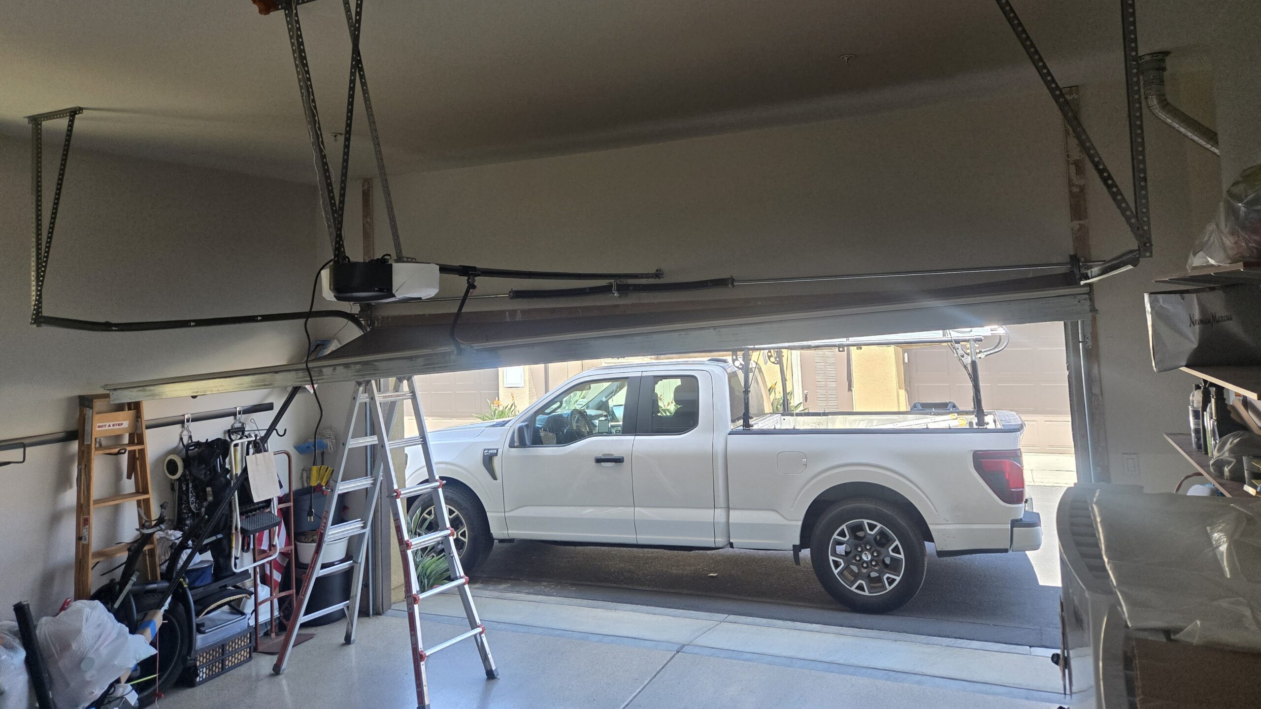 Off-track garage door repair in Santa Ana, CA, showing a garage door hanging unevenly from the track.