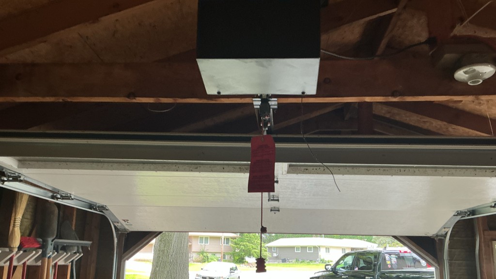 Garage door maintenance in Galesburg, IL, showing a ceiling-mounted opener and partially open sectional garage door.
