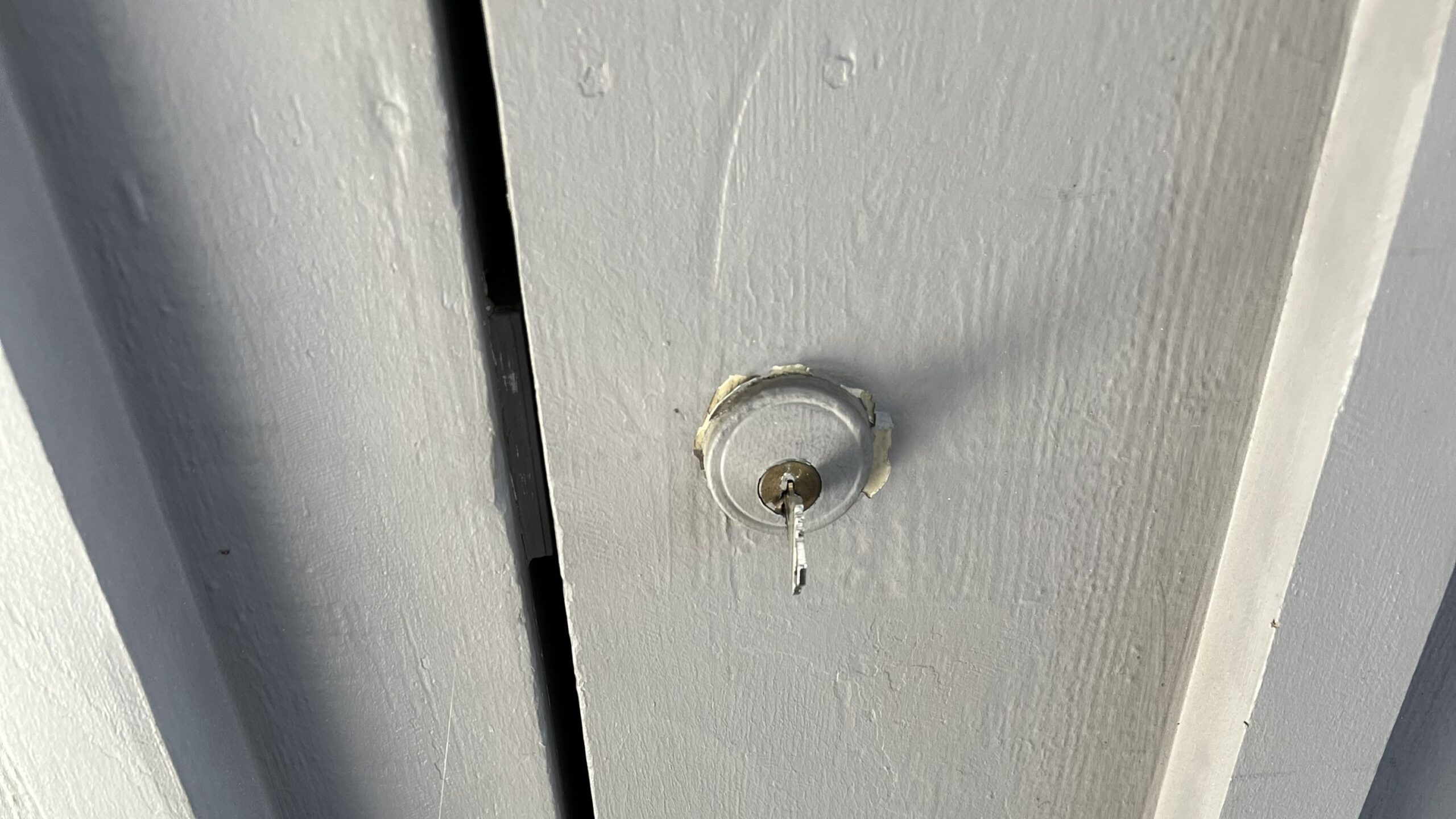 Close-up of a key inserted into a round door lock cylinder on a gray exterior door during an emergency locksmith service in Sherman Oaks, CA.