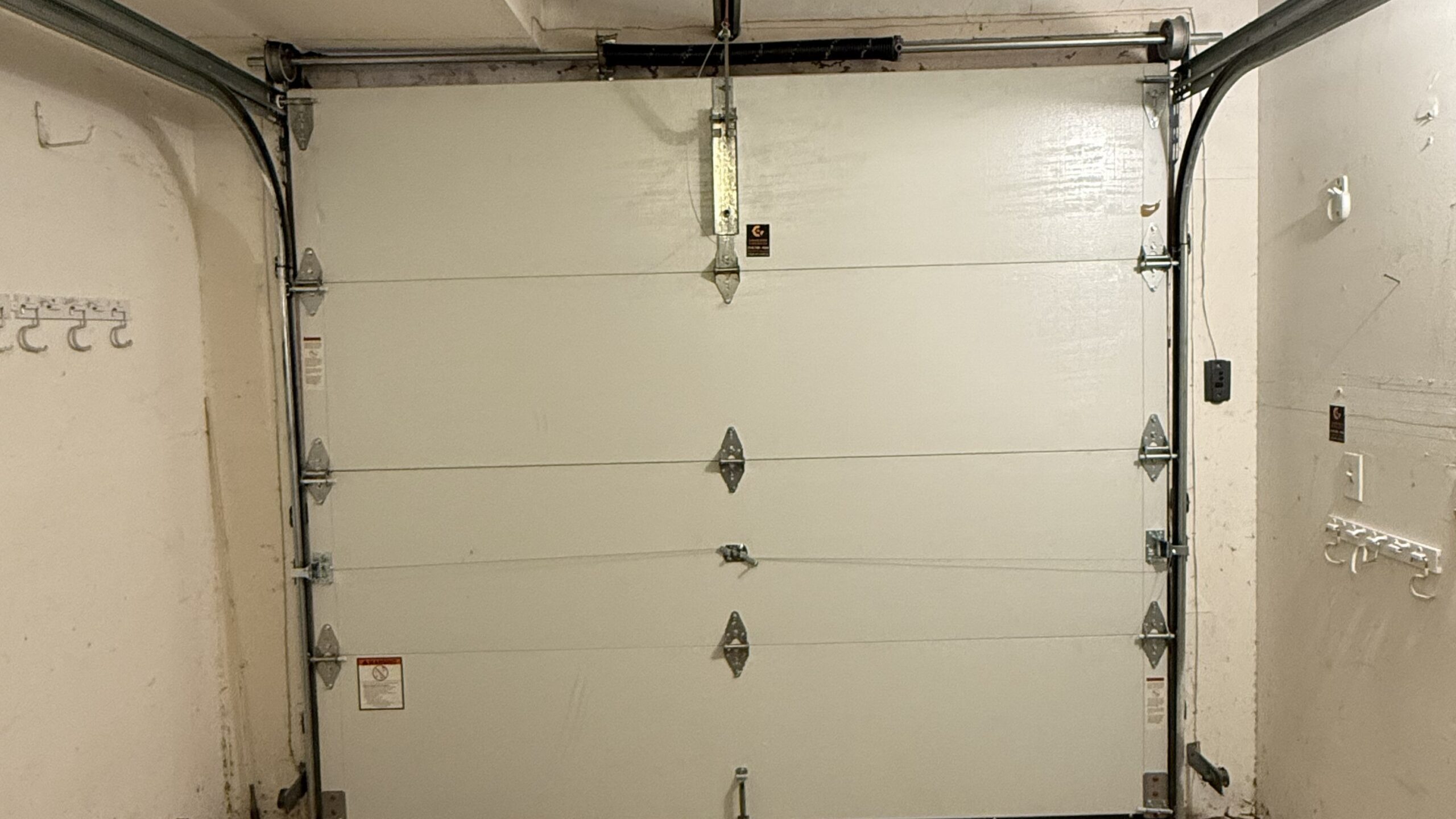 Garage door replacement in Santa Ana, CA, showing a sectional garage door with torsion spring, tracks, hinges, and mounting hardware.