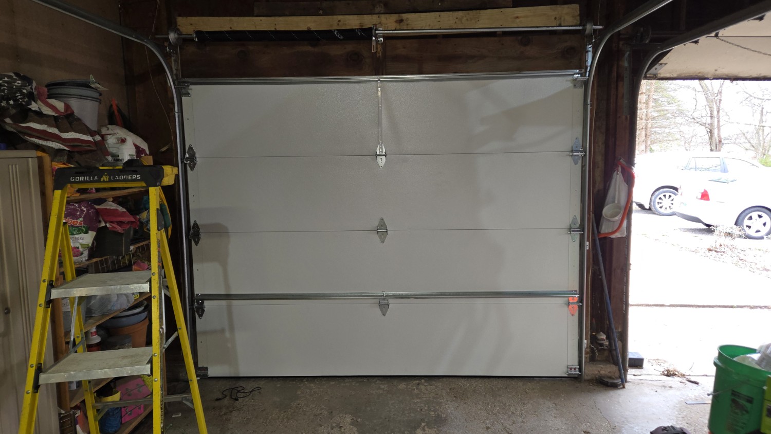 New garage door installation in Moline, IL, showing a white sectional garage door with new tracks, hinges, and torsion spring hardware.